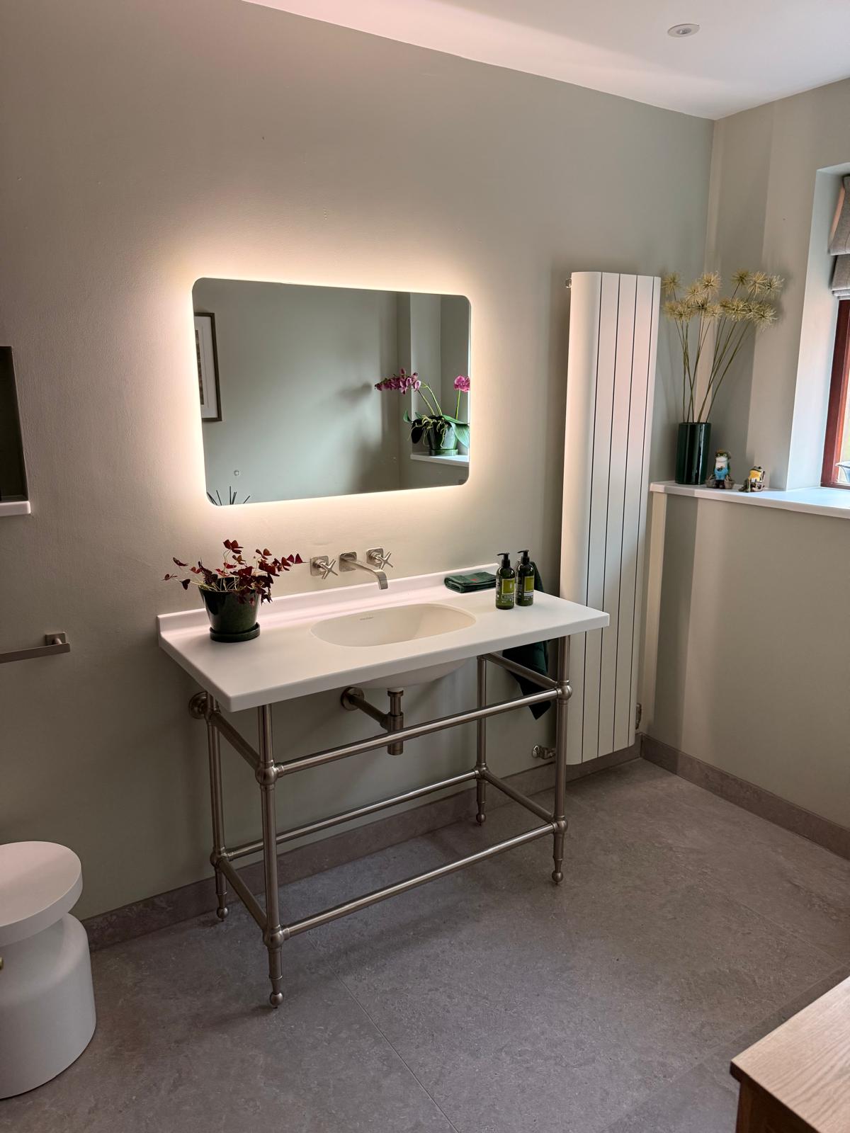 Basin on a chrome console frame with a backlit mirror and vertical radiator