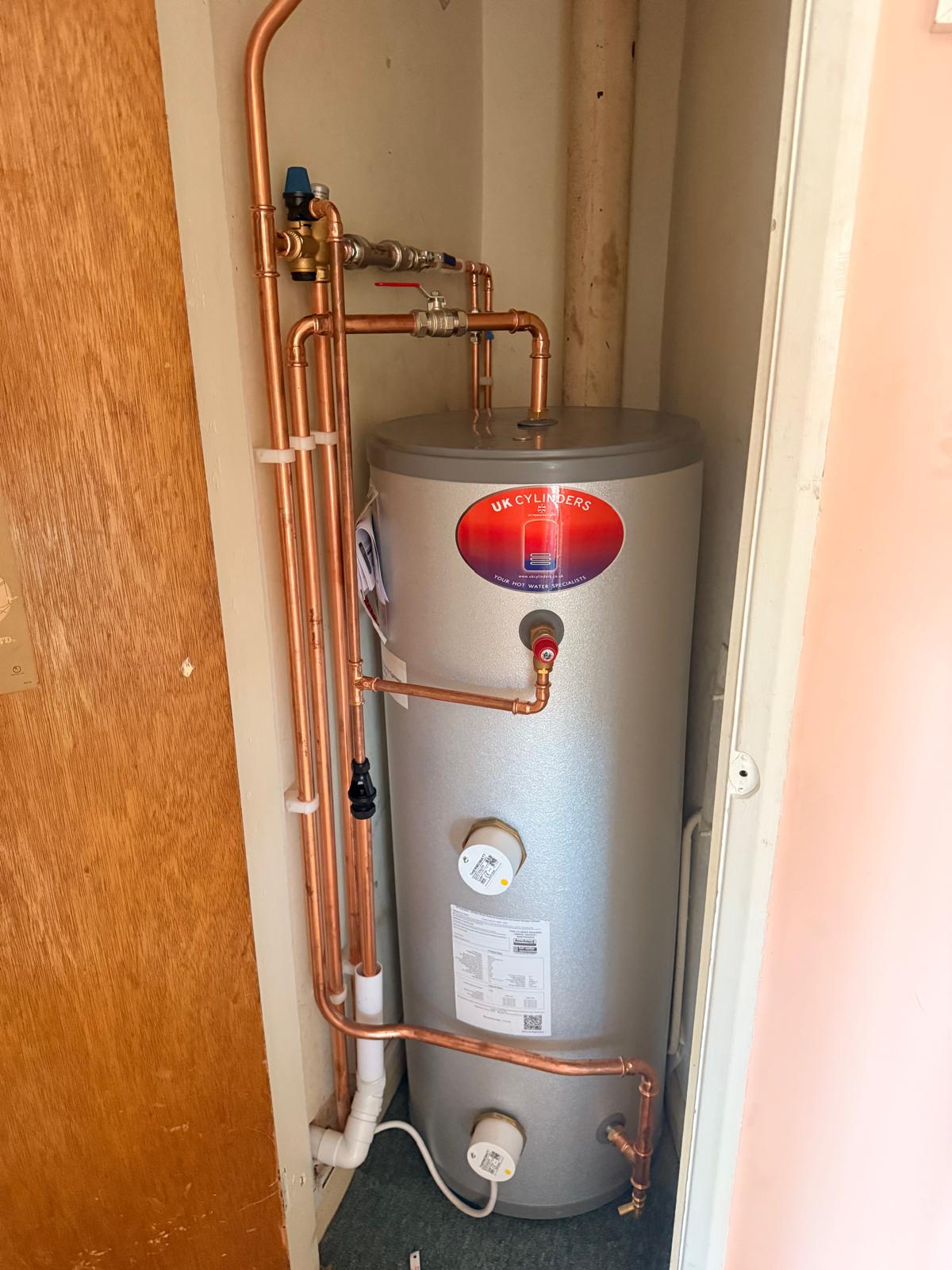 Unvented hot water cylinder with neat copper pipework in an airing cupboard