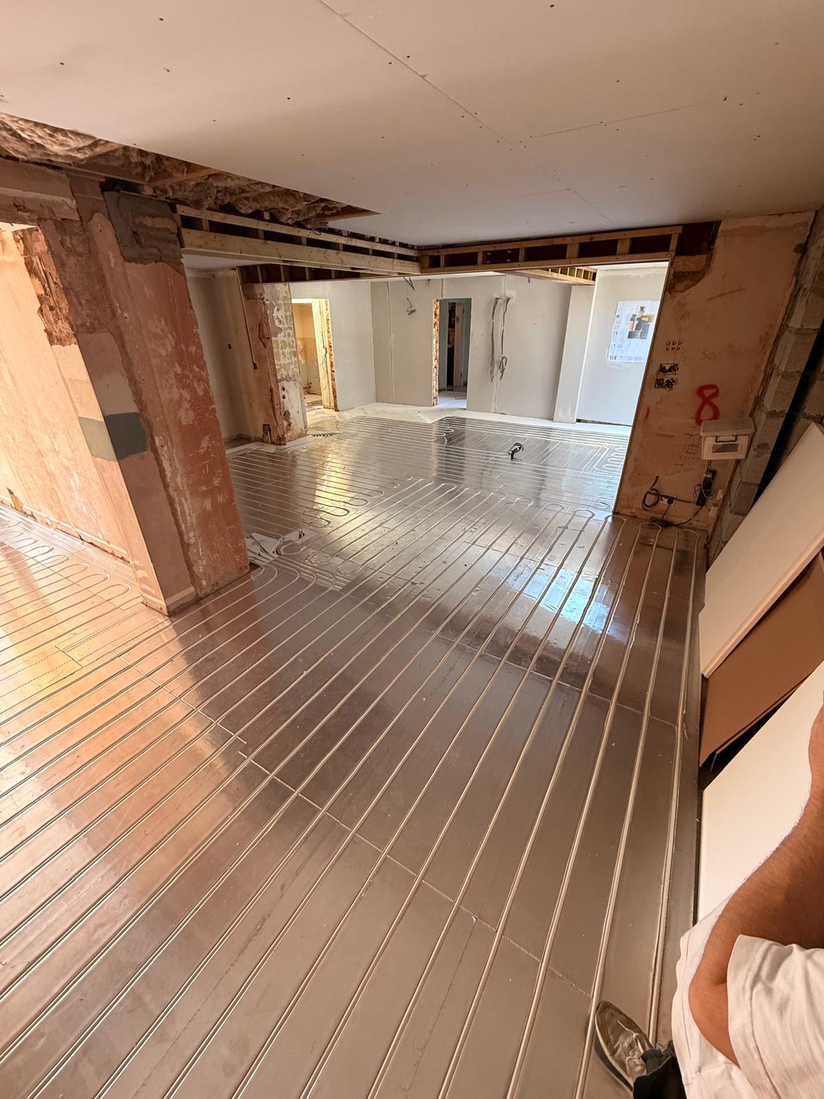 Underfloor heating panels being laid across a renovation ground floor
