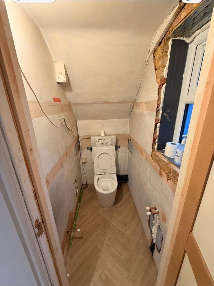 Cloakroom mid-renovation, stripped back to bare plaster with first-fix pipework