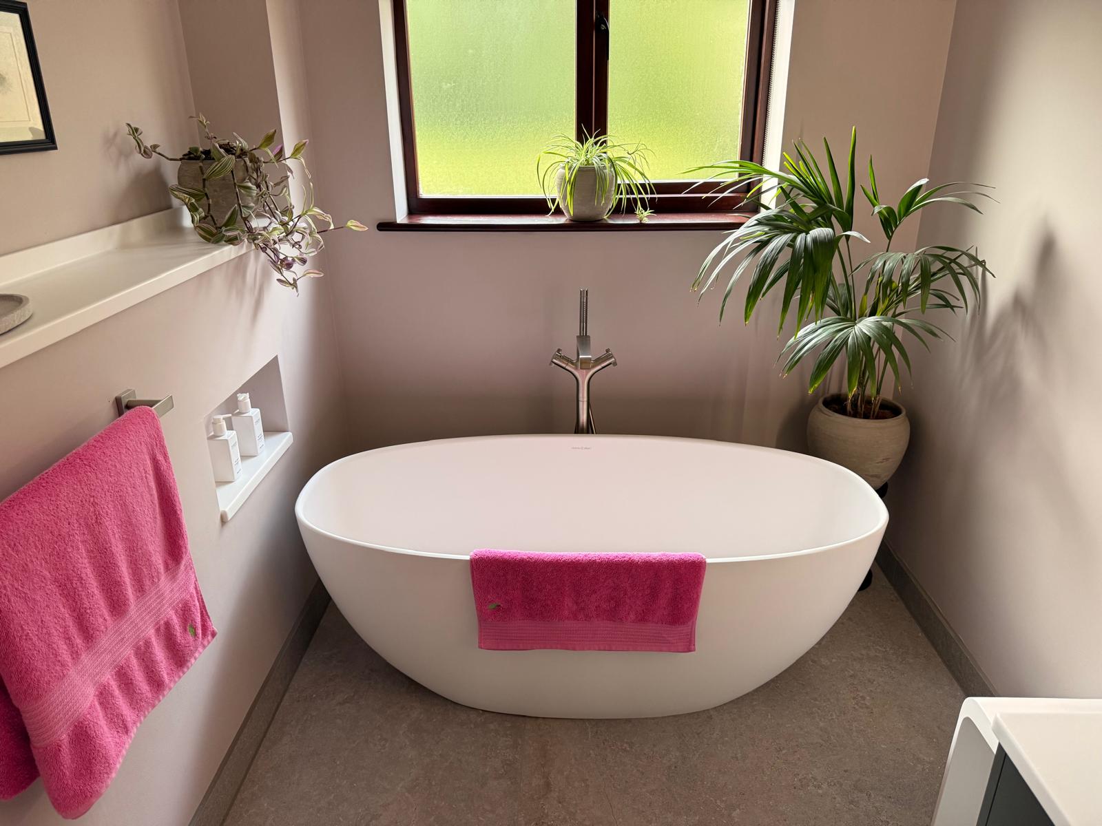Freestanding oval bath with a floor-standing tap beneath a window