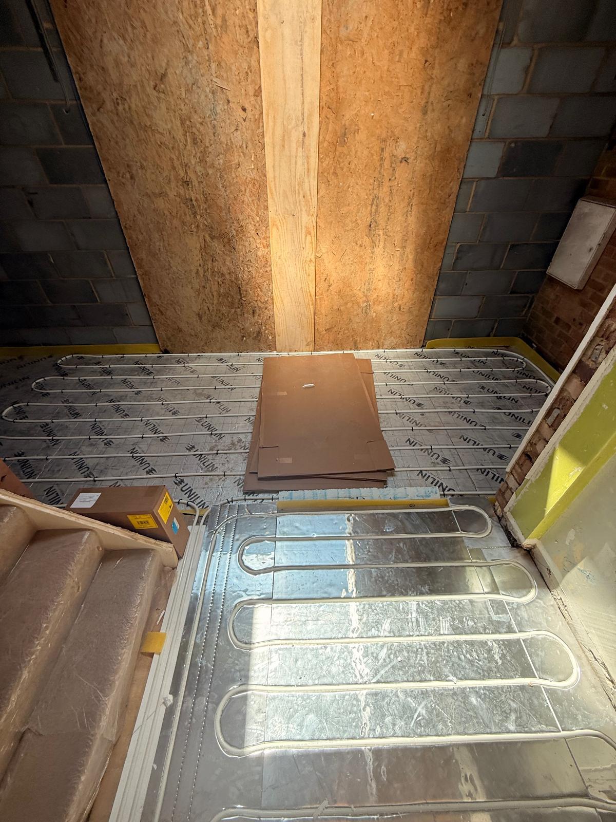 Underfloor heating pipe loops clipped to insulation in a small room